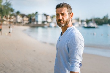 Ein Mann am Strand schaut in die Kamera und redet nicht