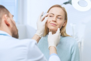 Ein Arzt erklärt einer Frau was ist Lifing und hält ihr Gesicht