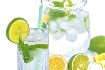 Auf und neben einem Glas Wasser sind Zitronen