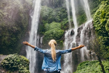 Eine Frau steht vor einem Wasserfall
