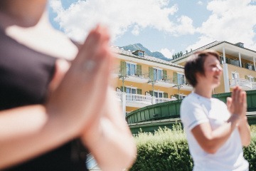 Zwei Frauen machen Yoga vor dem Alpenhaus Gasteinertal