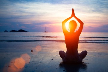 Jemand macht Yoga im Urlaub am Strand