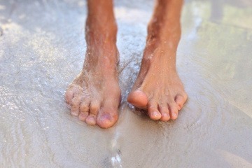 Füße im Wasser mit Zehen ohne Nagelpilz