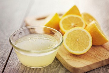 Zitronen liegen neben einer Schüssel Zitronensaft gegen Pickel