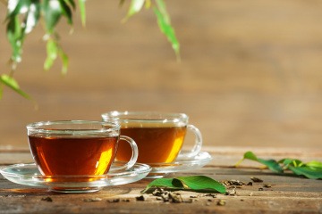 Zwei Tassen mit Tee stehen unter herabhängenden Blättern