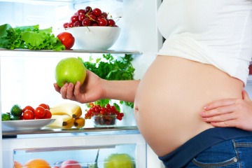 Eine schwangere Frau steht vor dem Kühlschrank