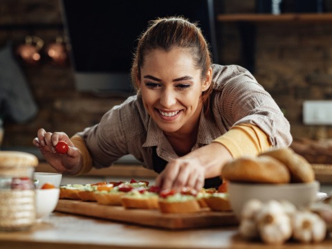 Mit ausgewogener Ernährung bist du das ganze Jahr über gut mit Nährstoffen versorgt Frau richtet Bruschetta in der Küche an